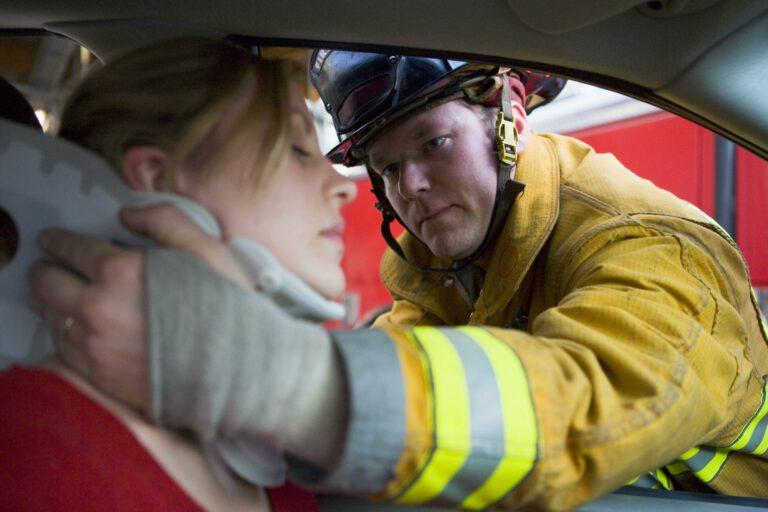 Feuerwehrmann hilft einer verletzten Frau im Fahrzeug