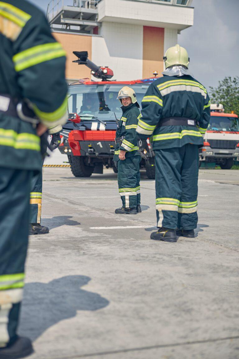 Feuerwehrmänner vor Feuerwehrauto an Fahrzeughalle