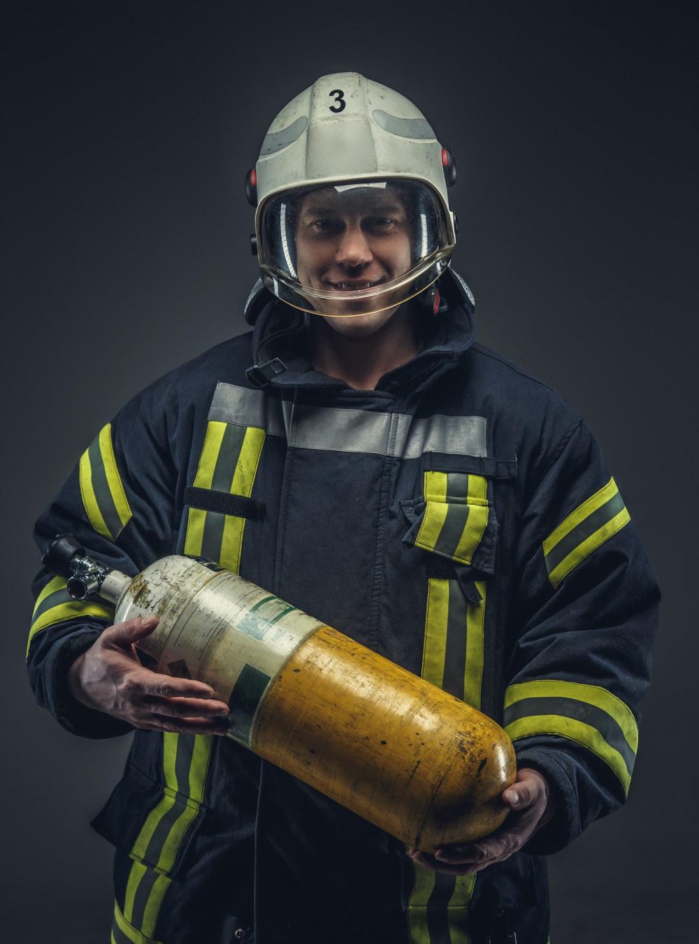 Feuerwehrmann mit Helm hält Sauerstoffflasche in der Hand
